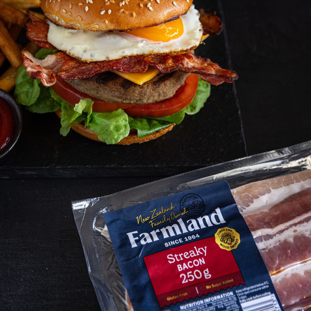 A hamburger with a pack of Farmland bacon in front