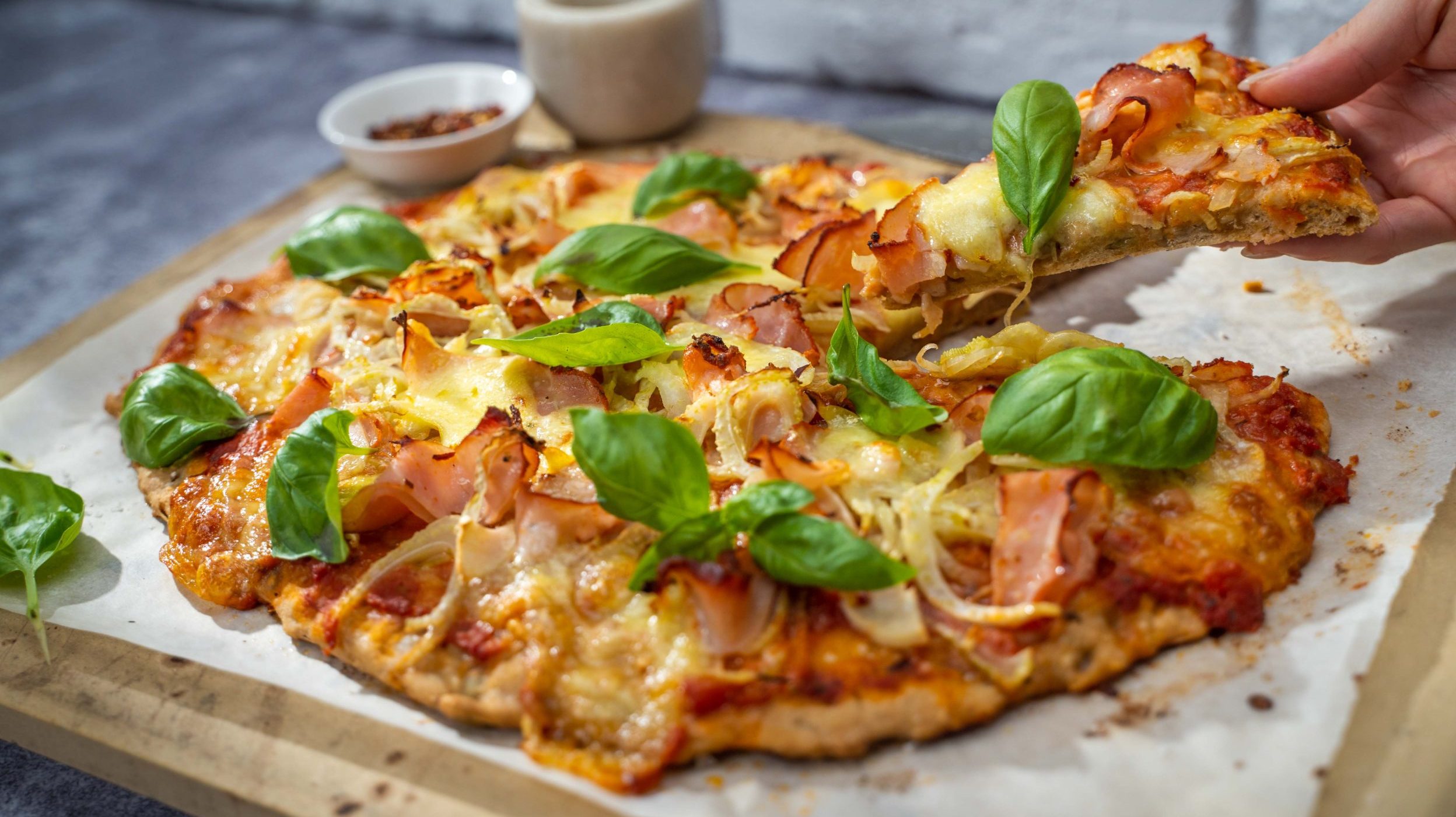 Pork and fennel pizza on a board with fresh basil