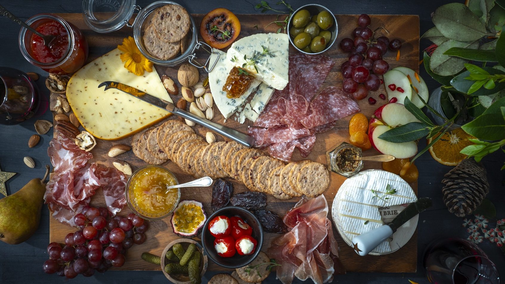 A topdown view of a large charcuterie board withwith a lot of gourmet foods.