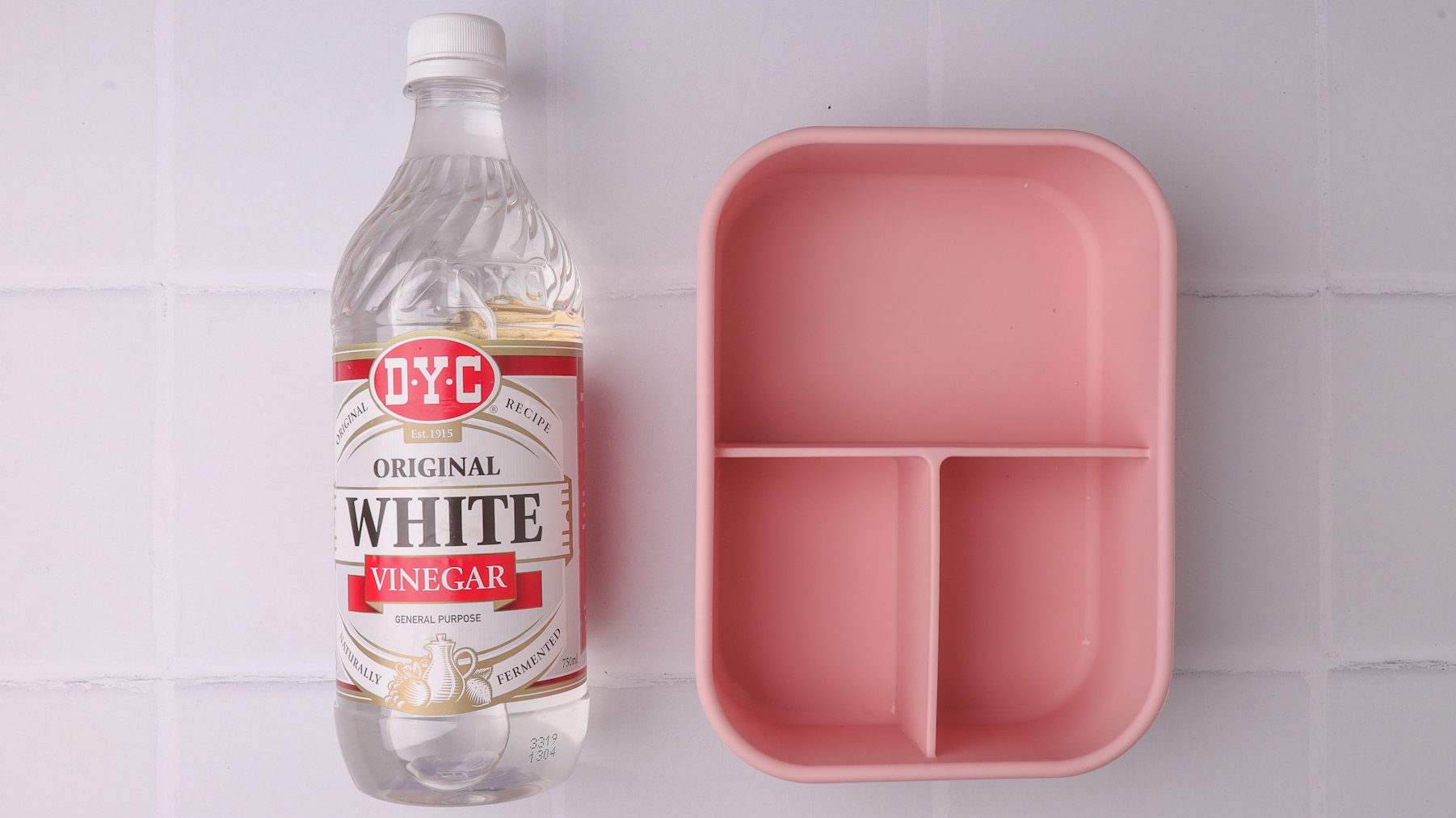 A bottle of vinegar and an empty pink lunch box.
