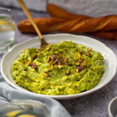 Garlic avocado dip with bread in the background