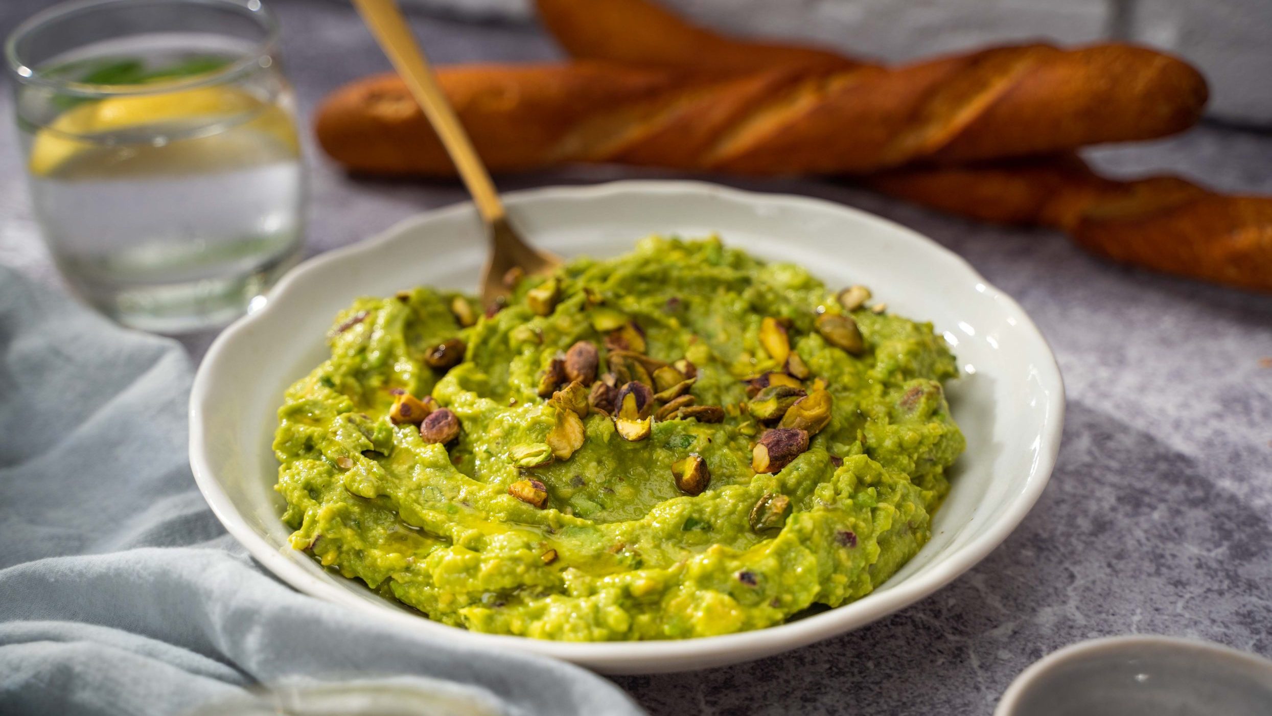 Garlic avocado dip with bread in the background