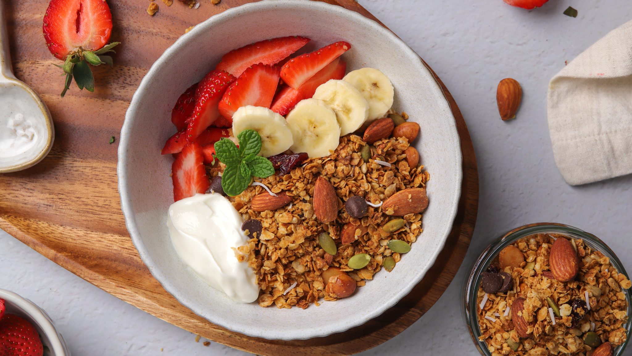 Granola and strawberries, banana and yoghurt in a white bowl.