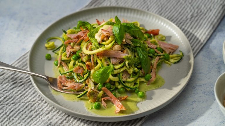 Green courgette salad with ham on a plate.