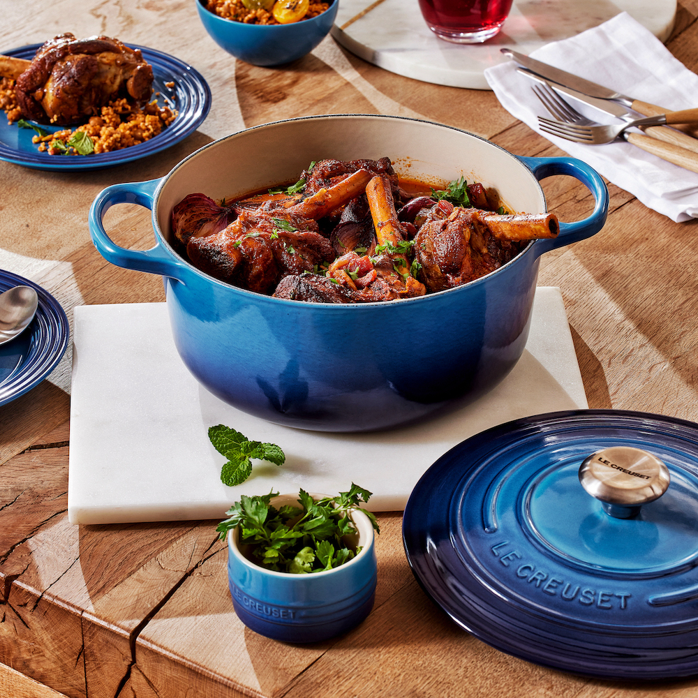 May must-haves 2023 - Le Creuset Azure collection blue casserole dish filled with lamb shanks on a wooden table