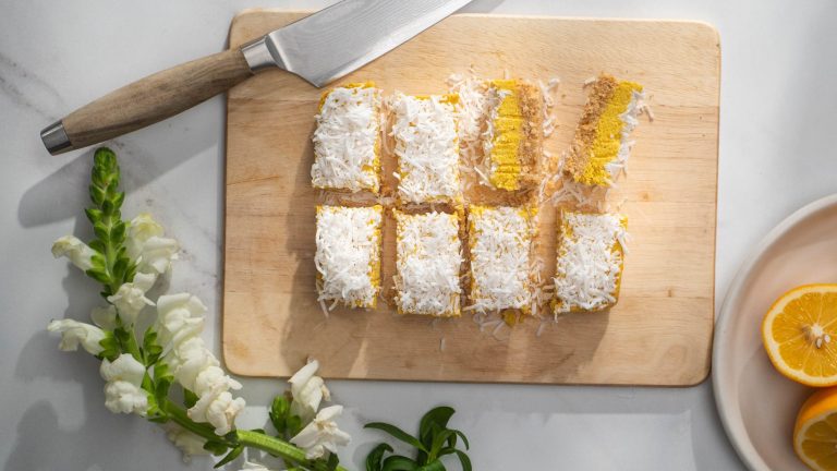 Eight pieces of white and yellow slices on a wooden board with knife.