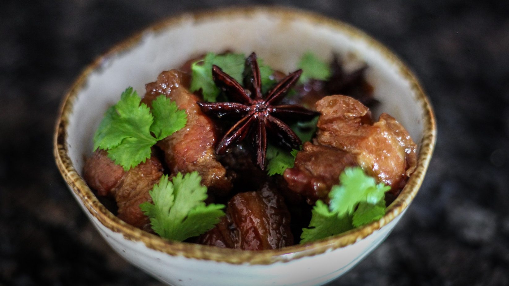 Moo Hong Braised pork belly in a bowl with star anise and fresh coriander leaves