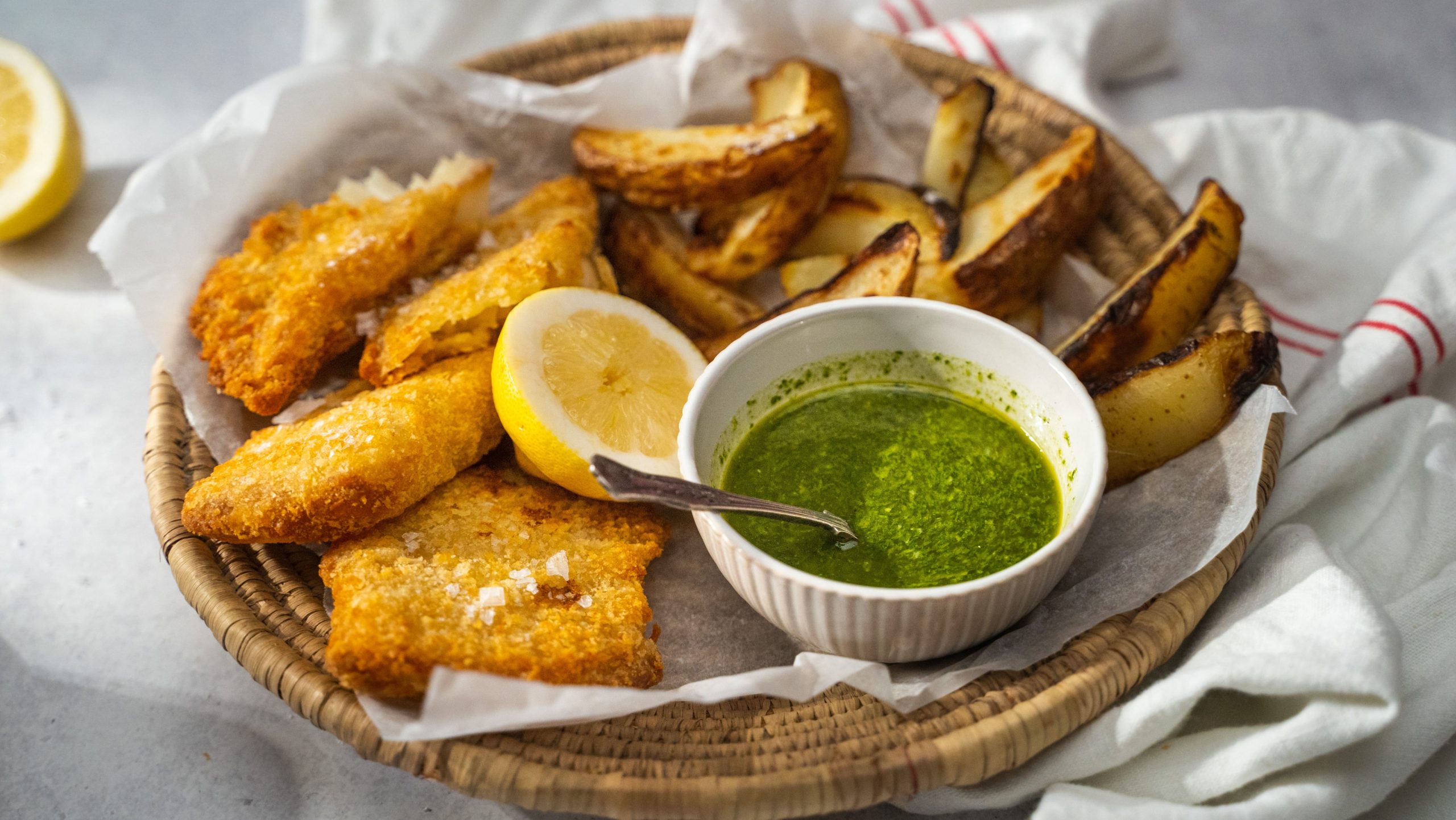 Easy lemon and herb dressing in a bowl served with crumbed fish and wedges.