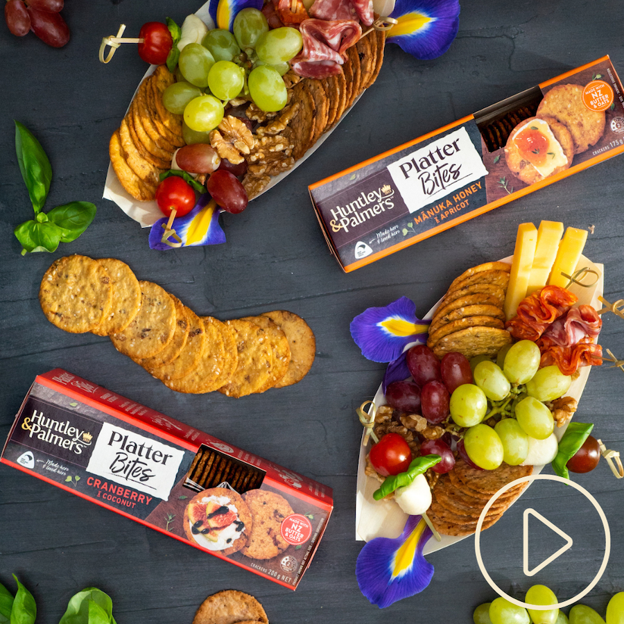 Crackers, grapes, cheese, and cocktail picks in small boats with packets of Huntley & Palmers Platter Bites crackers
