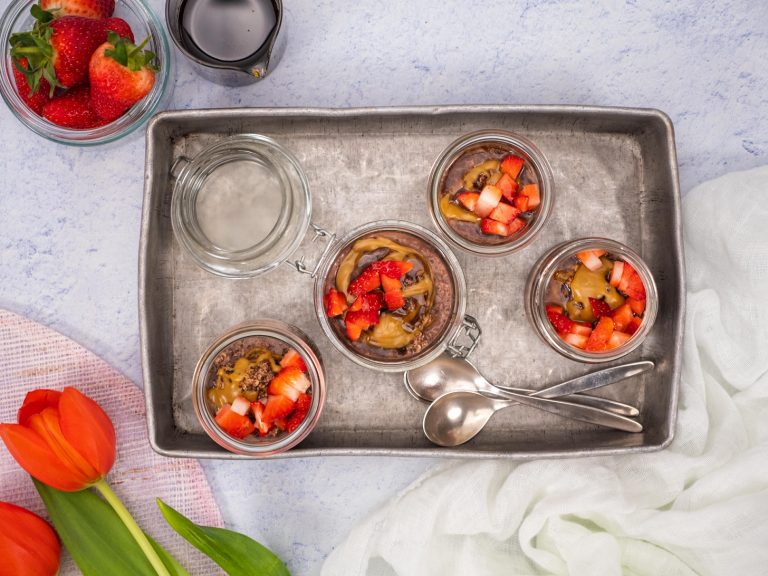 Four chocolate oat pottles presented in a tray, served in glass jars and topped with peaNOT butter and strawberries.