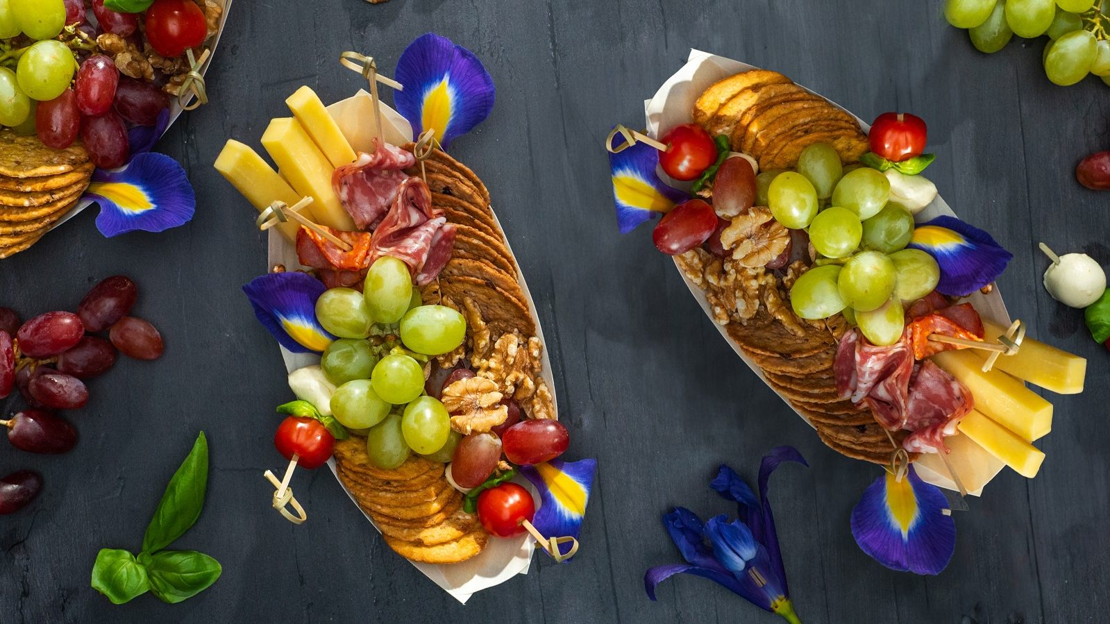 Crackers, grapes, cheese, and cocktail picks in small boats.