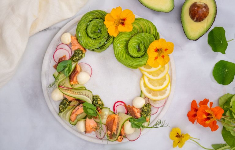 Smoked salmon wreath with highly decorative accents of edible flowers, lemon slices, fresh herbs and avocado slice spirals.
