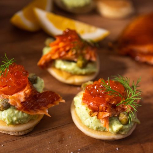 Three blinis topped with green cream, salmon flesh and salmon roe.
