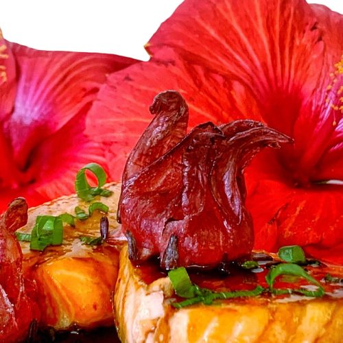 Salmon with ginger hibiscus glaze and fresh red hibiscus flowers