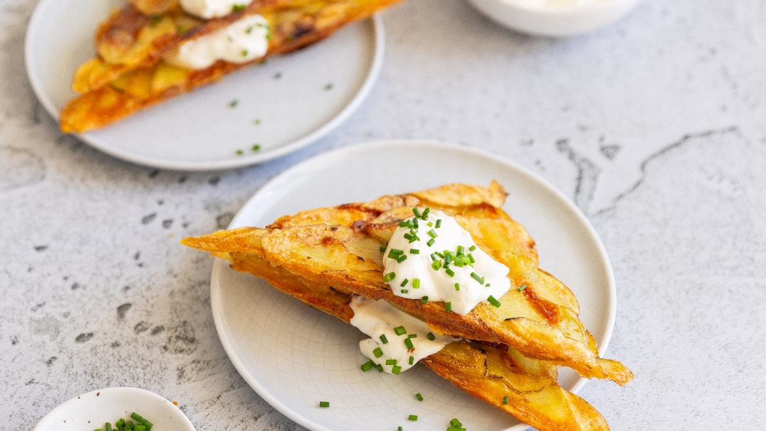 Two triangle toasties stack on a plate topped with cream and green herb. Another same plate in the back.