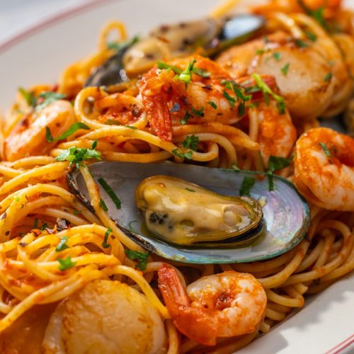 A plate of seafood spaghetti marinara sauce.