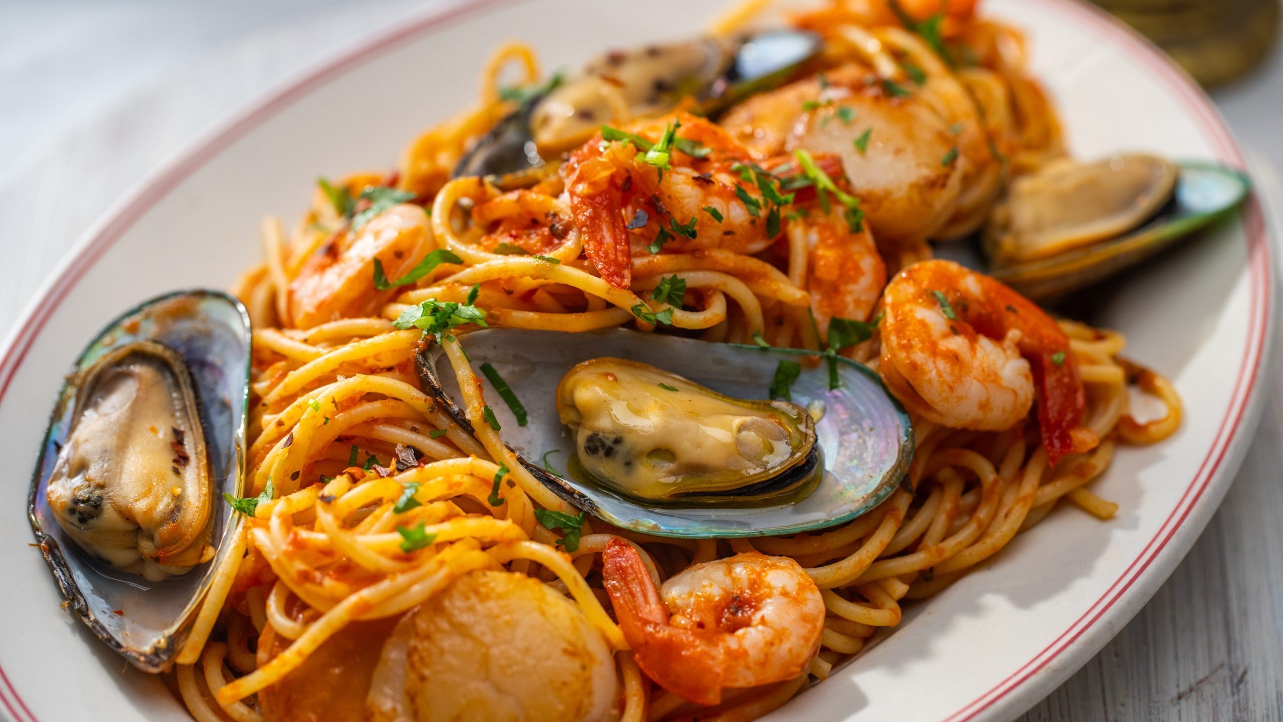 A plate of seafood spaghetti marinara sauce.