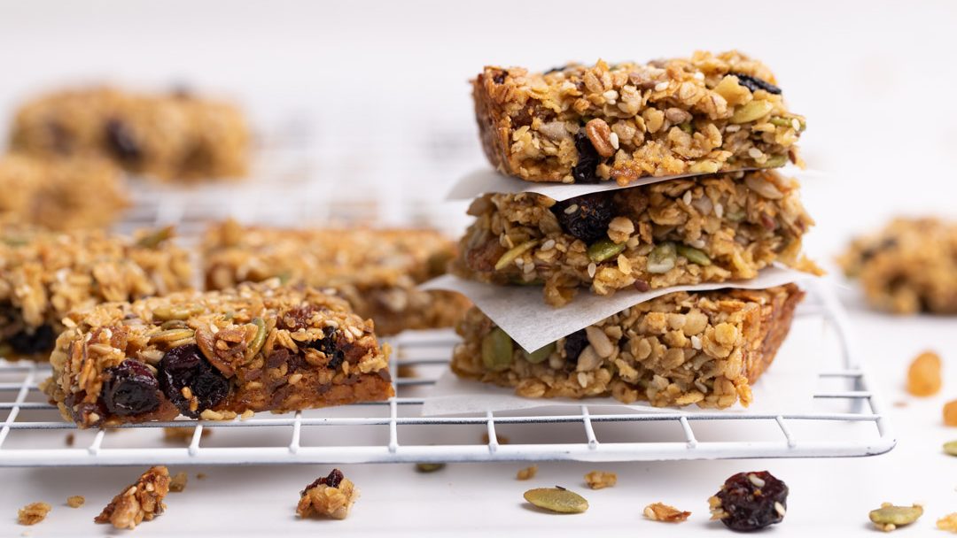 A stack of oats and seed slices and more on white wire rack.