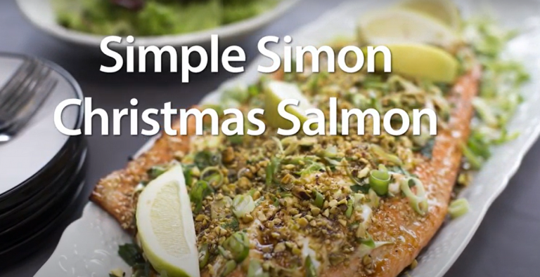 A whole side of cooked salmon topped with salad, nuts and lemon wedges. Simple Simon Christmas Salmon text over the image.