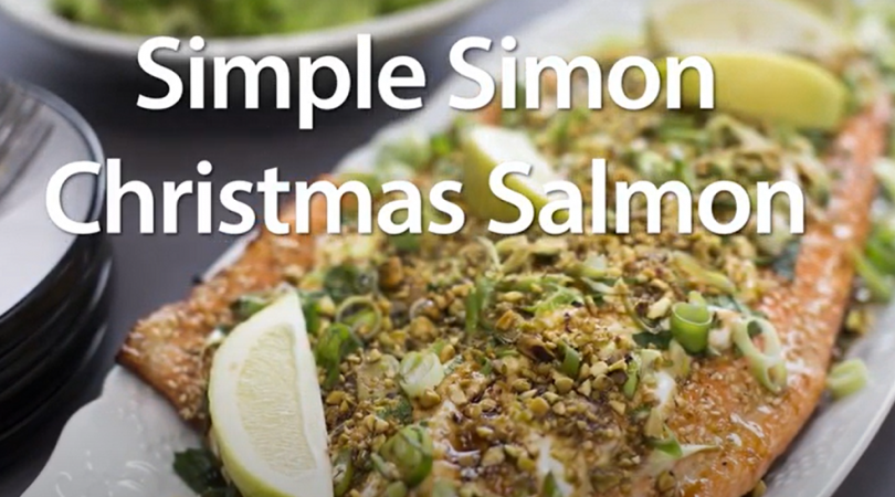 A whole side of cooked salmon topped with salad, nuts and lemon wedges. Simple Simon Christmas Salmon text over the image.