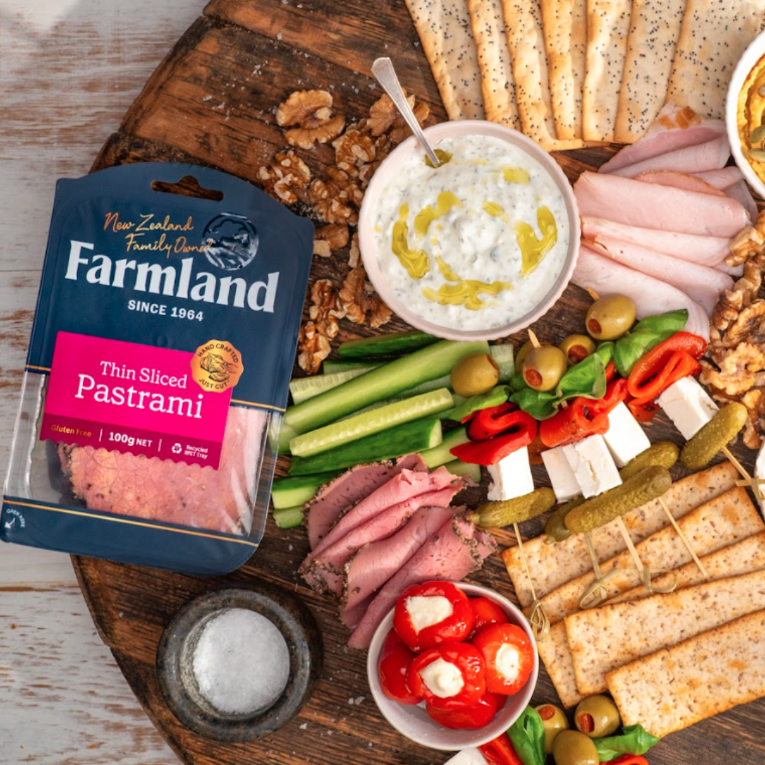 A platter of crackers, vegetables, cheeses etc featuring a packet of Farmland Pastrami
