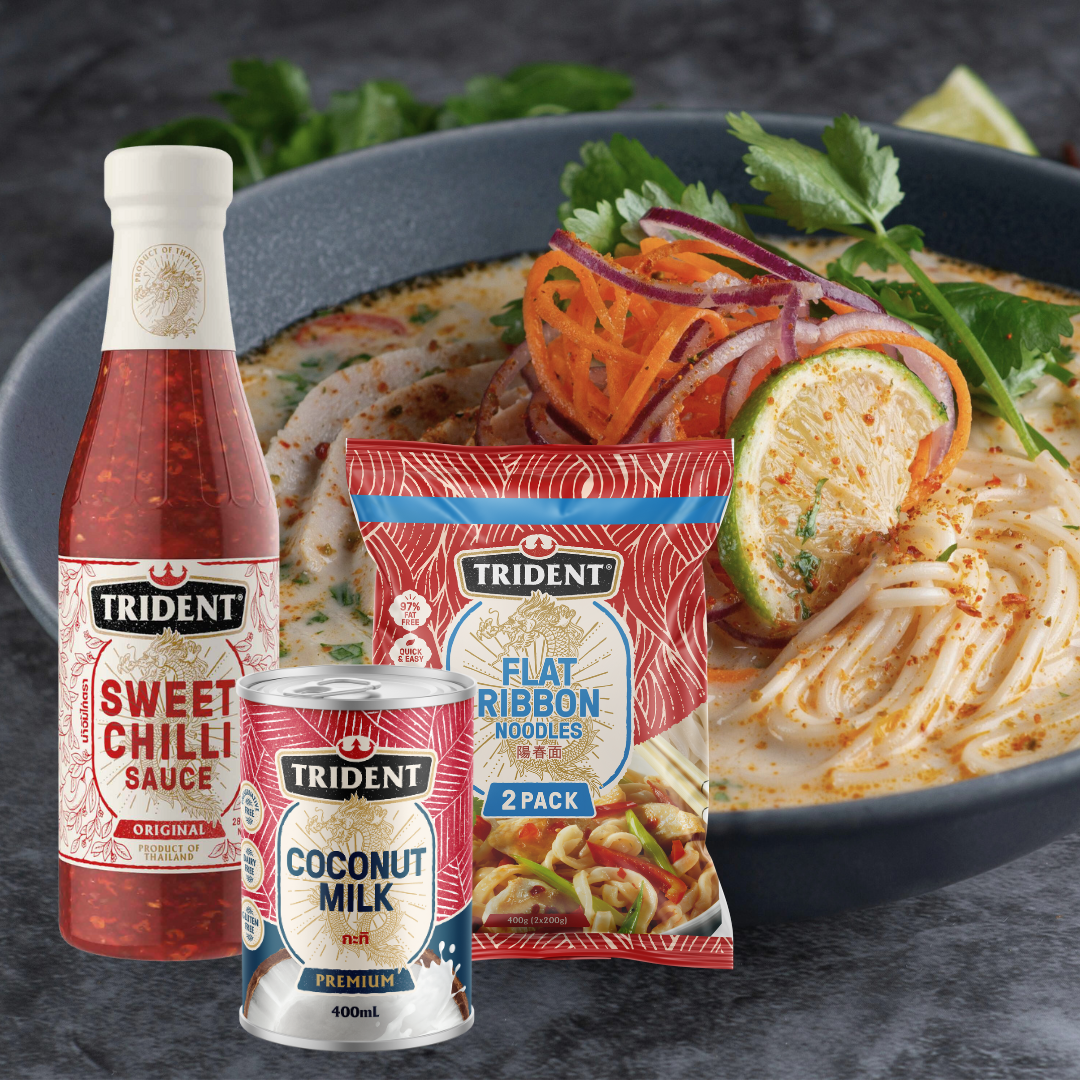 A bowl of noodle soup with a bottle of Trident Sweet Chilli Sauce, a packet of Trident Flat Noodles, and a can of Trident Coconut Miik