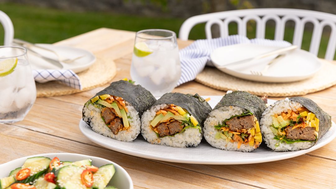 Four nori-wrapped sushi with meat and vegetables showing.