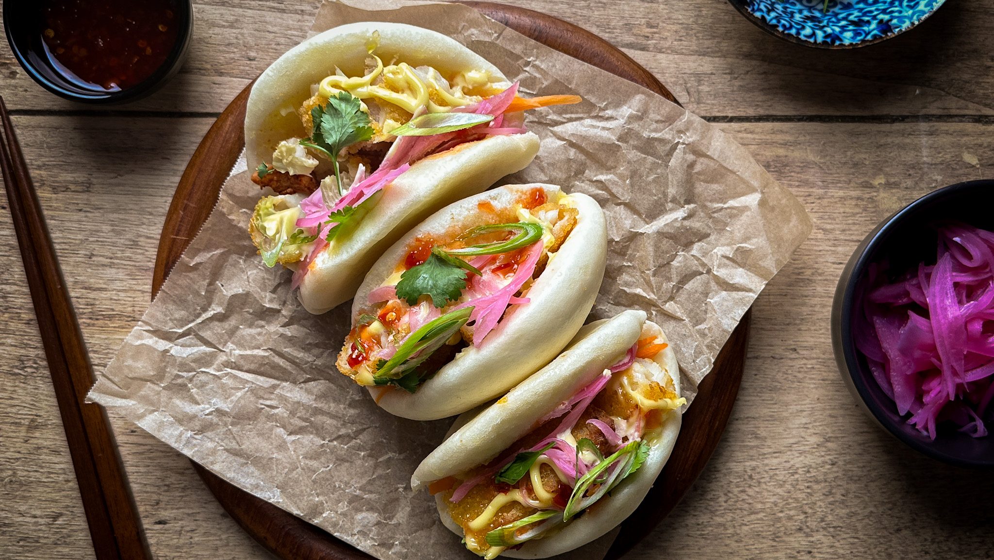 Three filled bao buns on a paper lined plate.