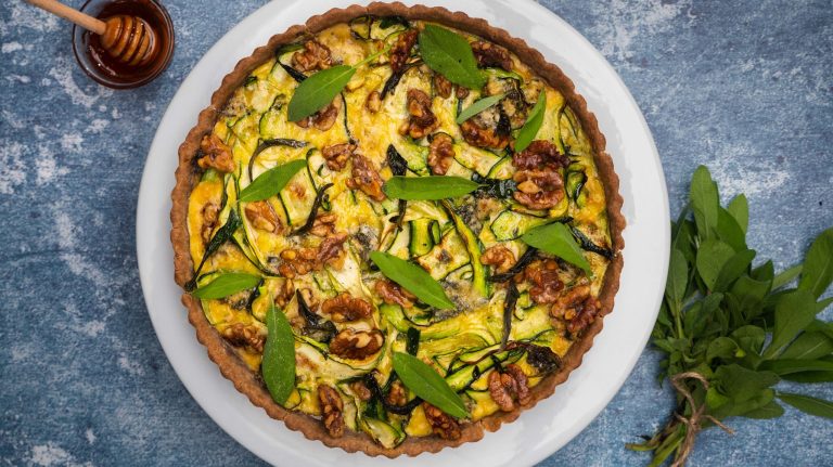 Round baked egg tart with green herbs and walnuts